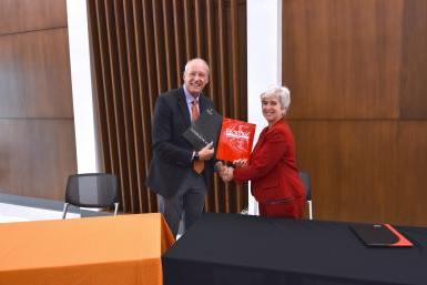 Dr. Leah Barrett, president of Northeast Community College, shakes hands with Dr. Roger Hughes, Doane president, after the two signed a renewal of an institutional agreement. 